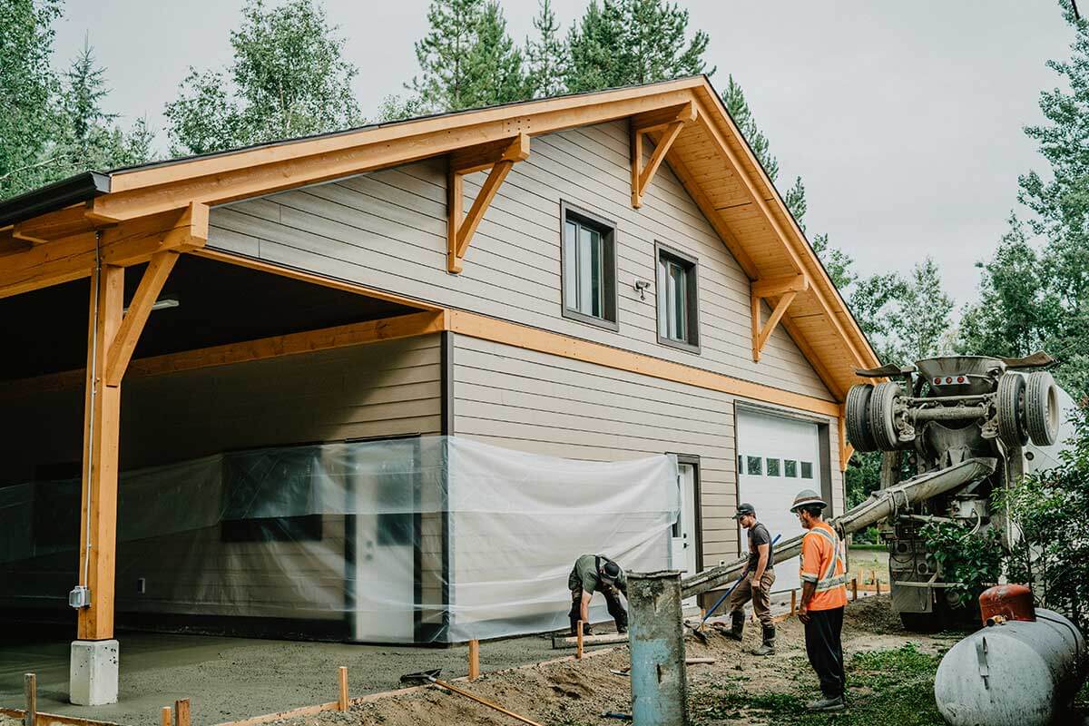 Construction of a Canadian timber frame building by Smith Timber Works, showing exposed wood structure, prefabricated wall panels, and crew at work, highlighting design-build and prefabrication processes in British Columbia.