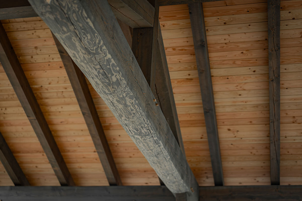 Close-up of interior timber frame ceiling with large exposed beams and natural wood planking, highlighting the quality and detail of Smith Timber Works' craftsmanship.
