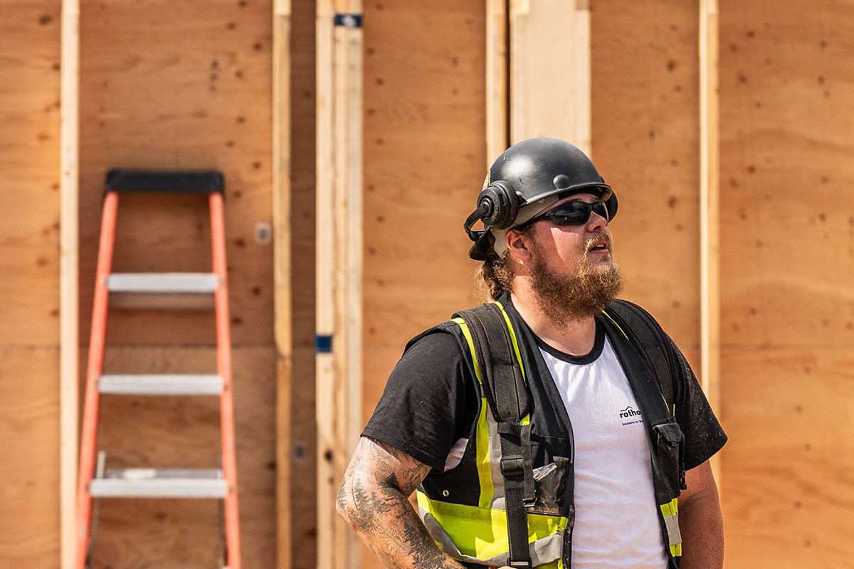 Smith Timber Works crew member on-site during timber framing, wearing safety gear in front of a structural plywood wall.