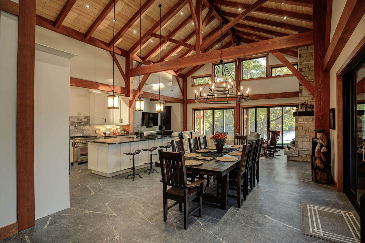 Expansive open-concept interior of a timber frame home by Smith Timber Works, featuring exposed trusses, a gourmet kitchen, and a spacious dining area, showcasing Canadian design and craftsmanship.