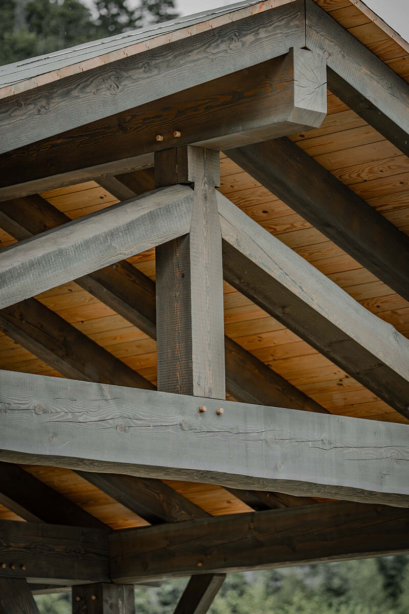 Close-up of exterior timber frame roof structure with exposed beams and planking, demonstrating durable design and expert craftsmanship by Smith Timber Works.