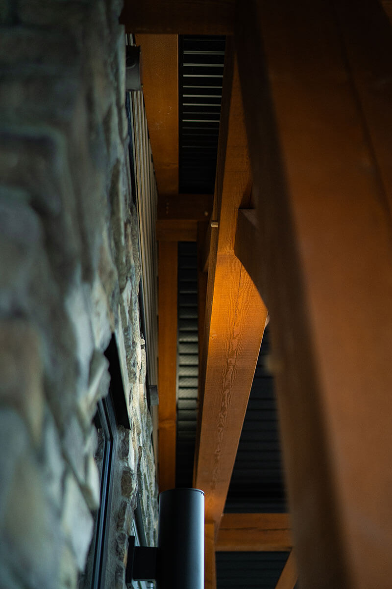 Detail of timber frame structural connection and stone wall by Smith Timber Works, showcasing quality Canadian craftsmanship.