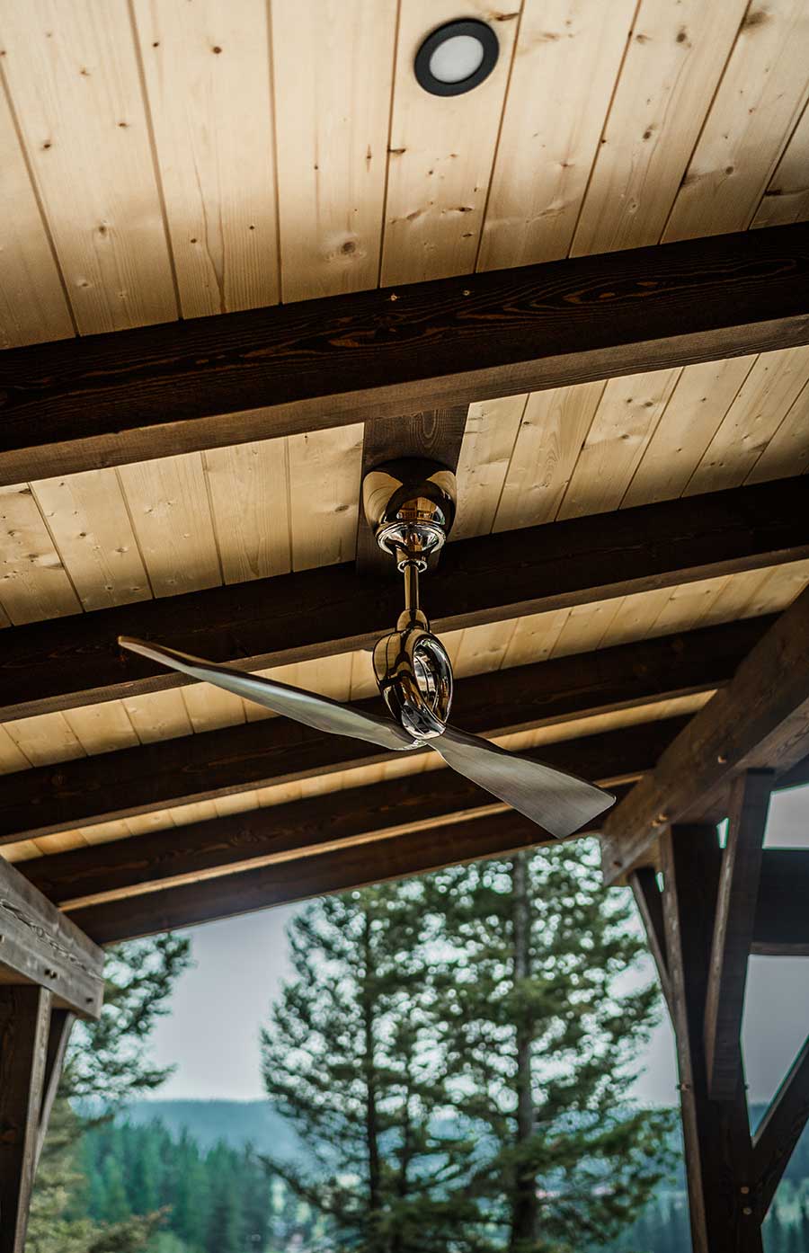 Outdoor timber frame patio ceiling with exposed wood beams and planking, featuring a modern ceiling fan, reflecting custom design and craftsmanship by Smith Timber Works.