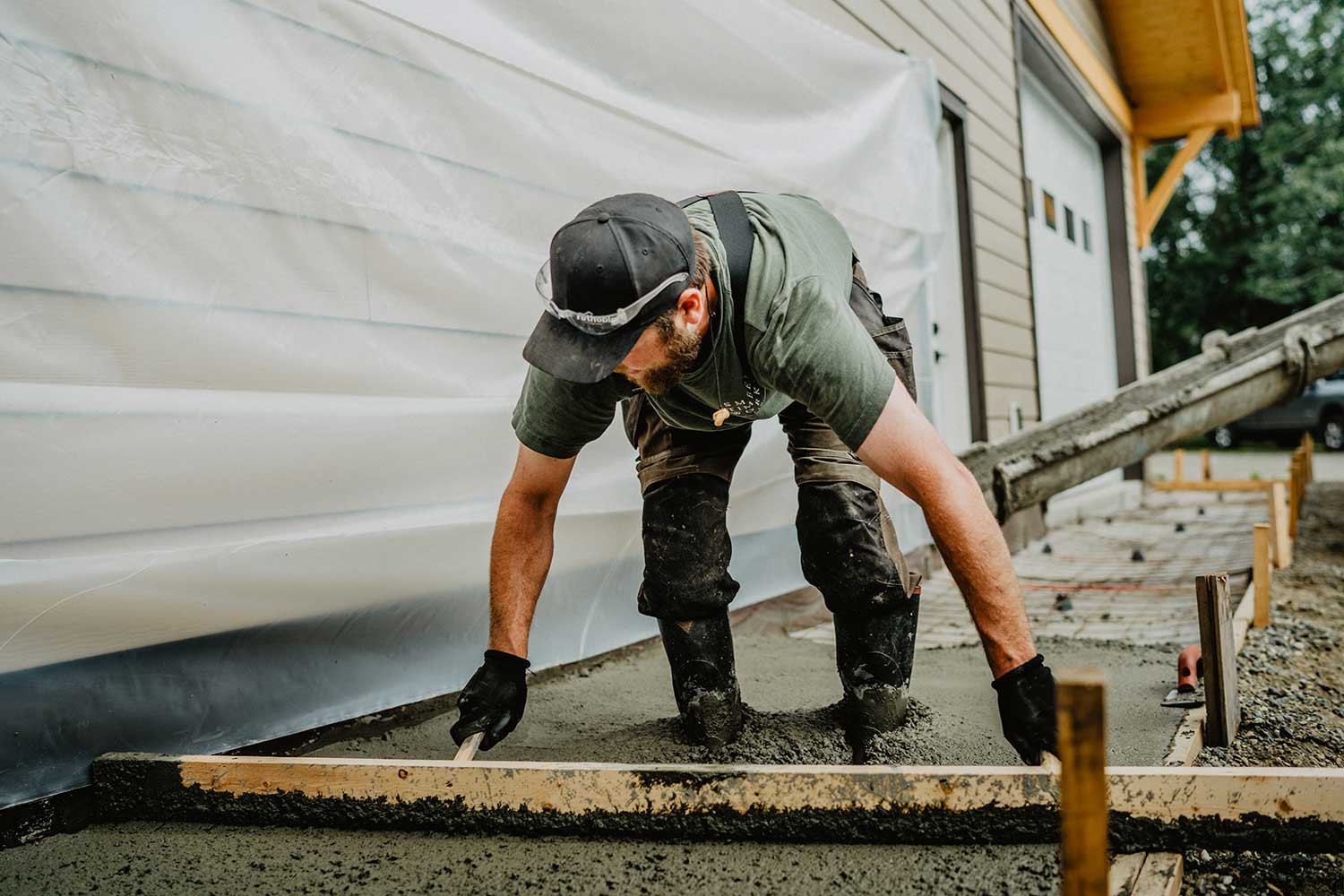 Construction worker pouring concrete for a foundation, representing the skilled labor and comprehensive build process by Smith Timber Works for Canadian timber frame projects.