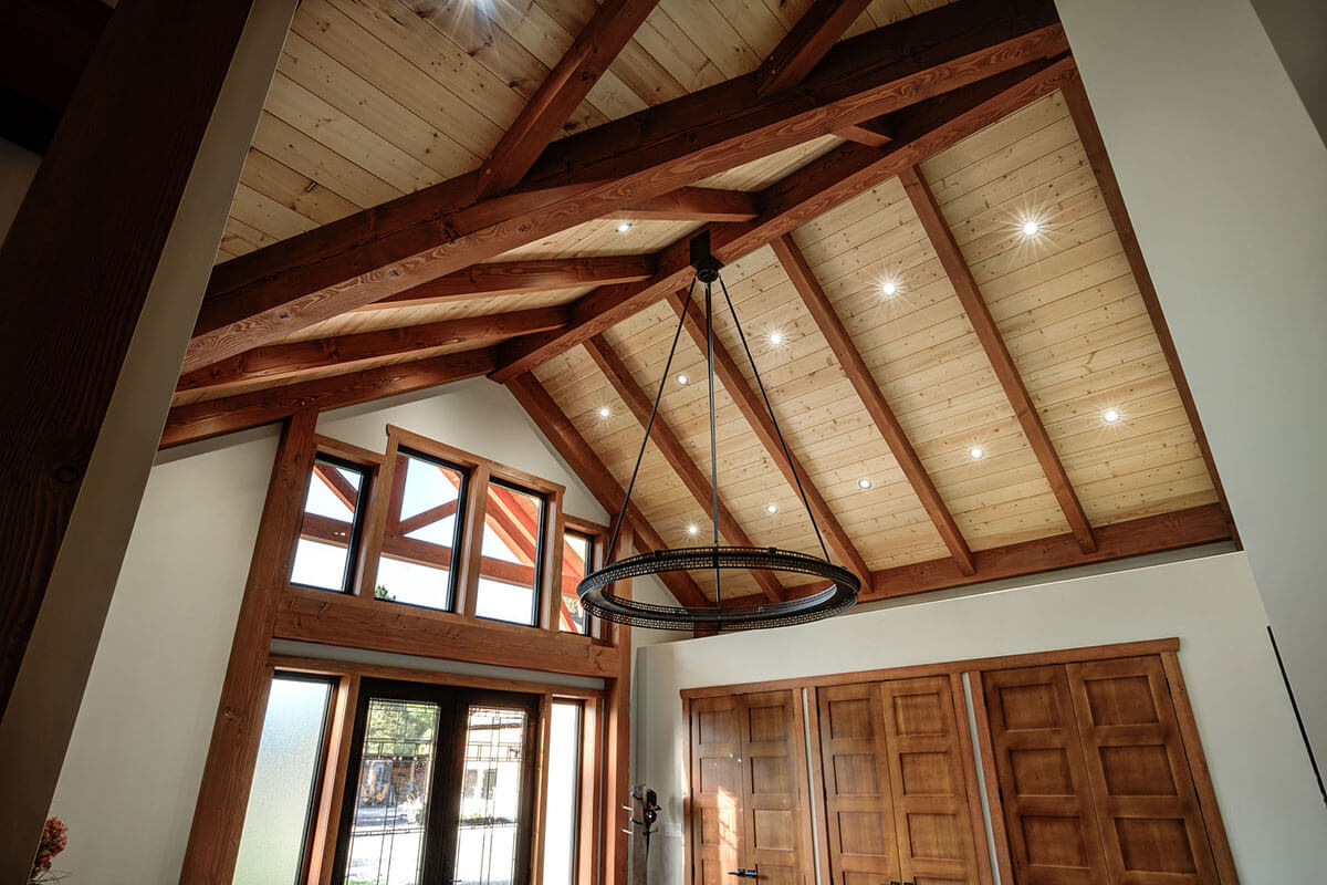 Interior view of a stunning timber frame ceiling with exposed wood beams and recessed lighting, showcasing the intricate design and craftsmanship by Smith Timber Works in British Columbia.