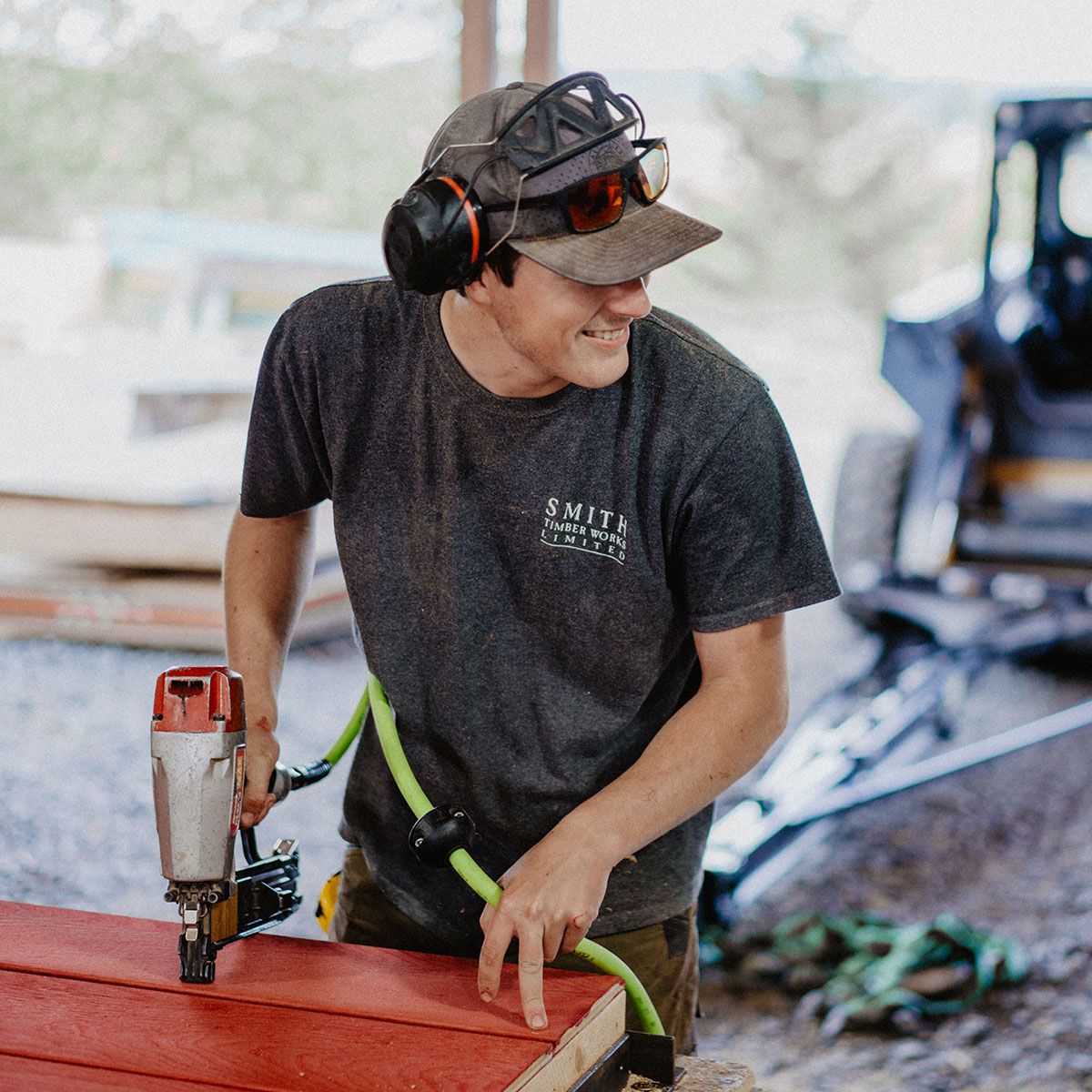 Smith Timber Works team member using a pneumatic nailer in the shop, fabricating prefinished framing components with care and precision.
