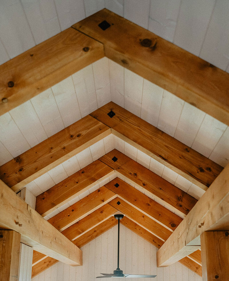 Vaulted timber ceiling with exposed wooden beams and a central black ceiling fan.