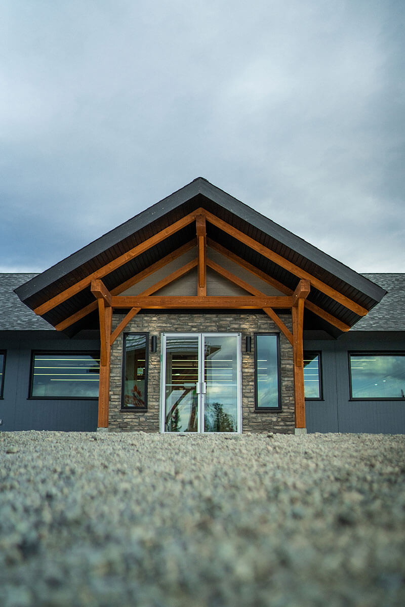 Smith Timber Works designed entry with exposed timber framing and stone, showcasing Canadian craftsmanship in British Columbia.