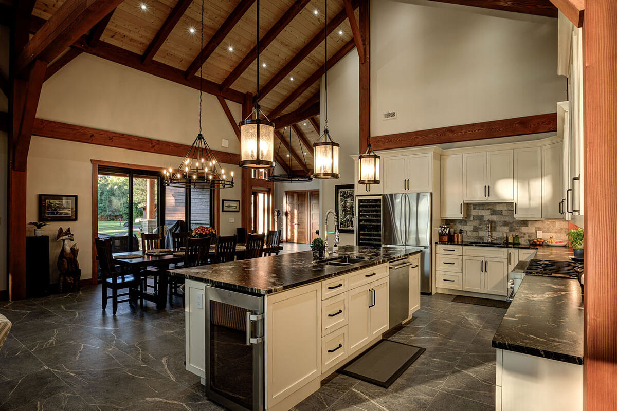 Spacious open-concept kitchen and dining area in a Canadian timber frame home by Smith Timber Works, featuring exposed wooden beams, modern appliances, and elegant lighting.