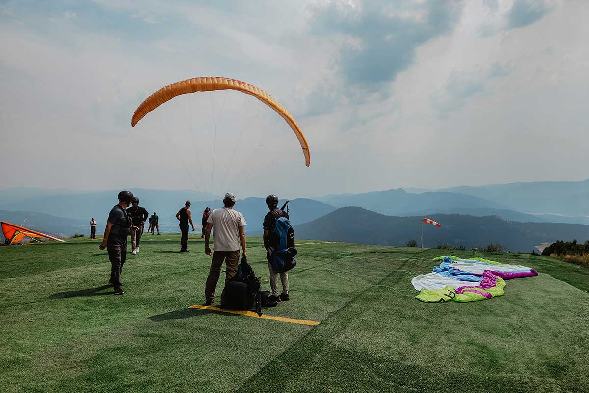 Paragliders preparing for launch above scenic mountain ranges in British Columbia, capturing the adventurous spirit that fuels Smith Timber Works.
