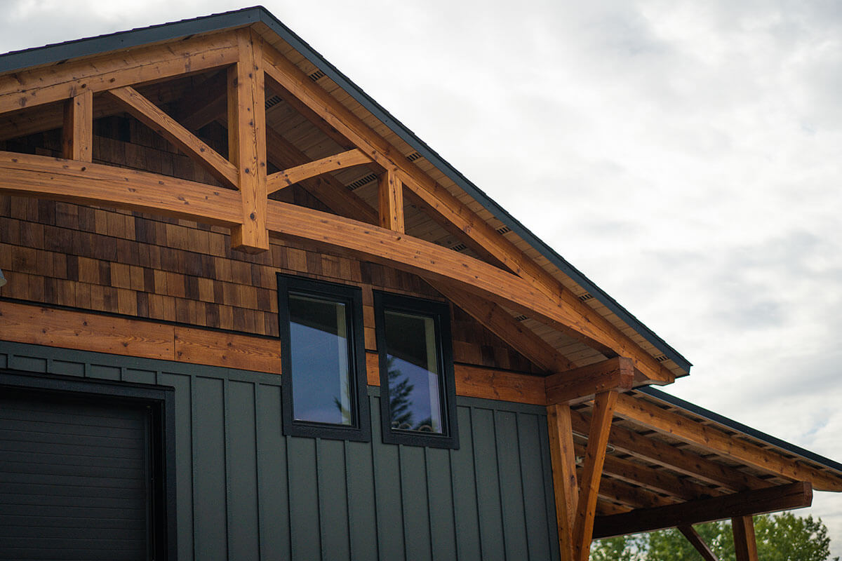 Timber frame workshop or outbuilding by Smith Timber Works, showcasing exposed structural timbers, dark siding, and an attached covered area, set in British Columbia.