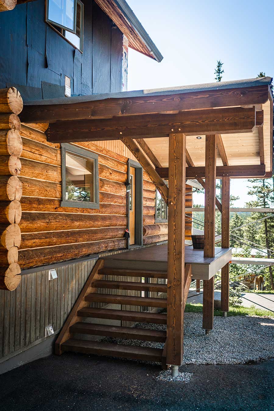 Custom timber frame entrance with log siding and a covered porch, showcasing Canadian craftsmanship and design by Smith Timber Works in British Columbia.