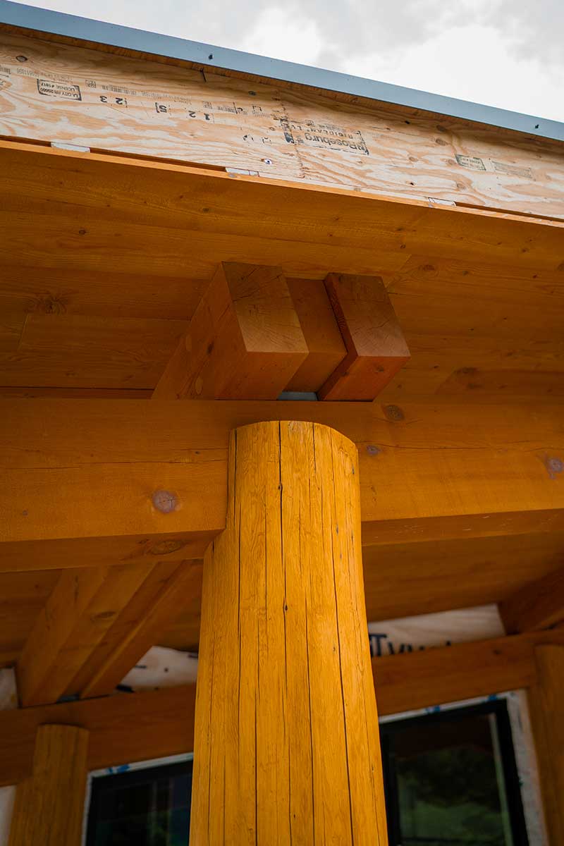 Detail of a large timber column and exposed beam on a building by Smith Timber Works, showcasing robust Canadian timber framing and natural wood finishes.