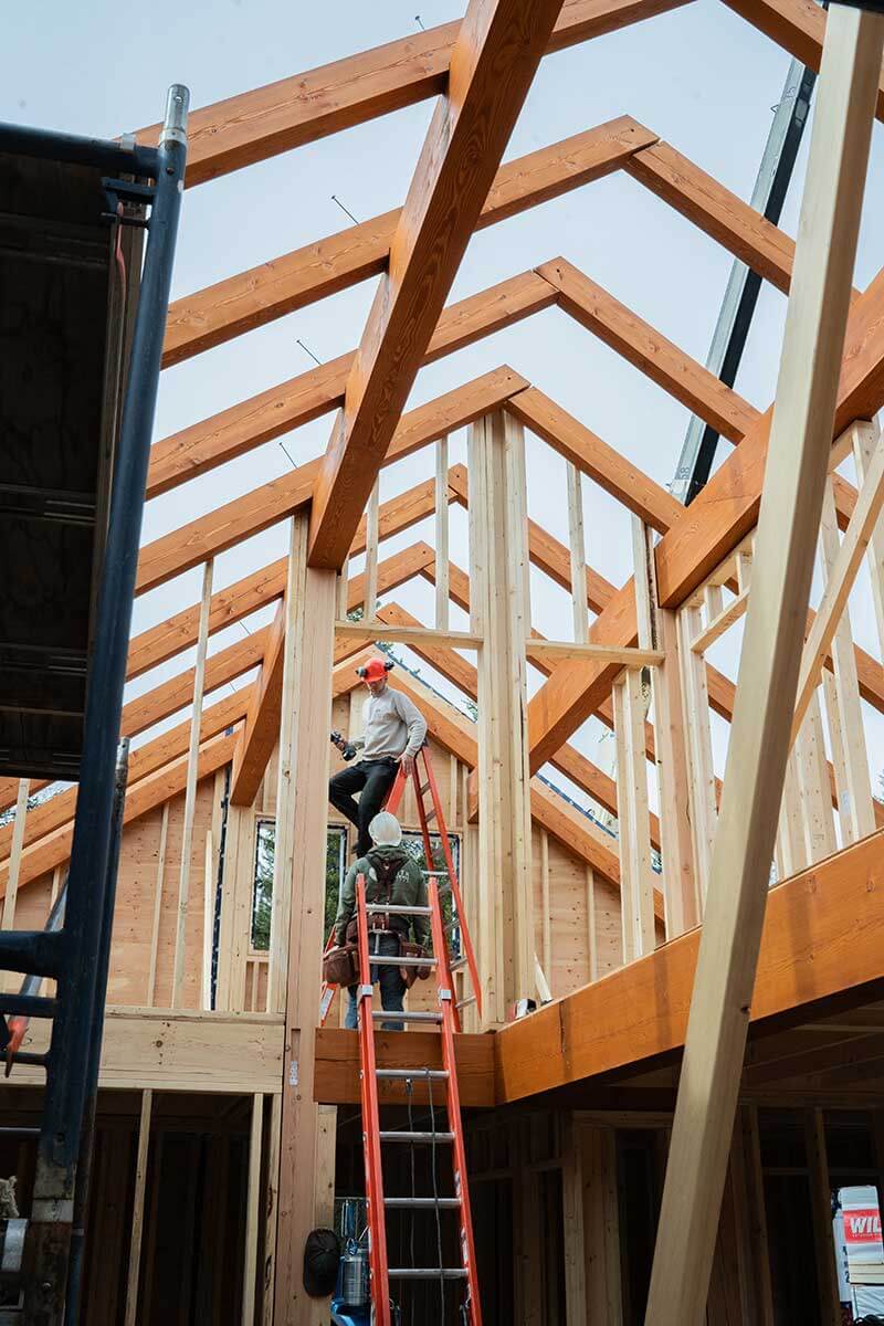Carpenter working on timber frame roof construction by Smith Timber Works, British Columbia.