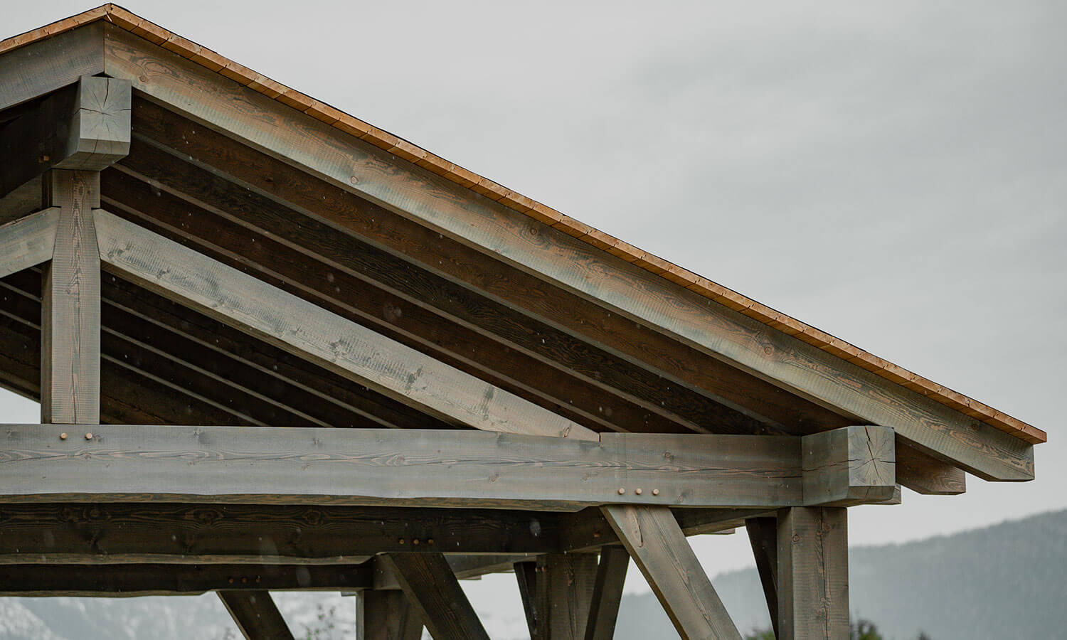 Close-up of a timber frame roof structure with exposed rafter tails and planking, showcasing robust Canadian design and build quality by Smith Timber Works.