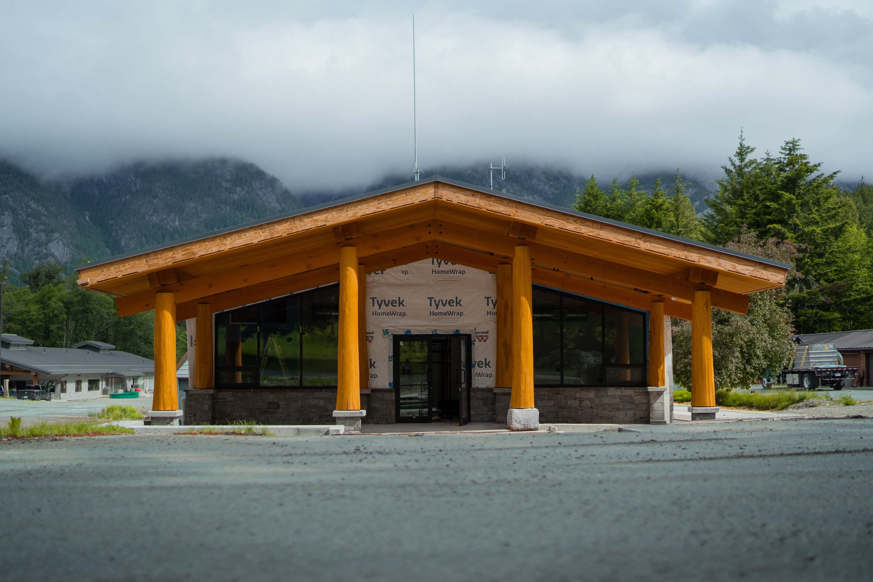 Commercial timber frame building under construction by Smith Timber Works in British Columbia, featuring prominent wooden columns and a broad roof, showcasing durable Canadian design.