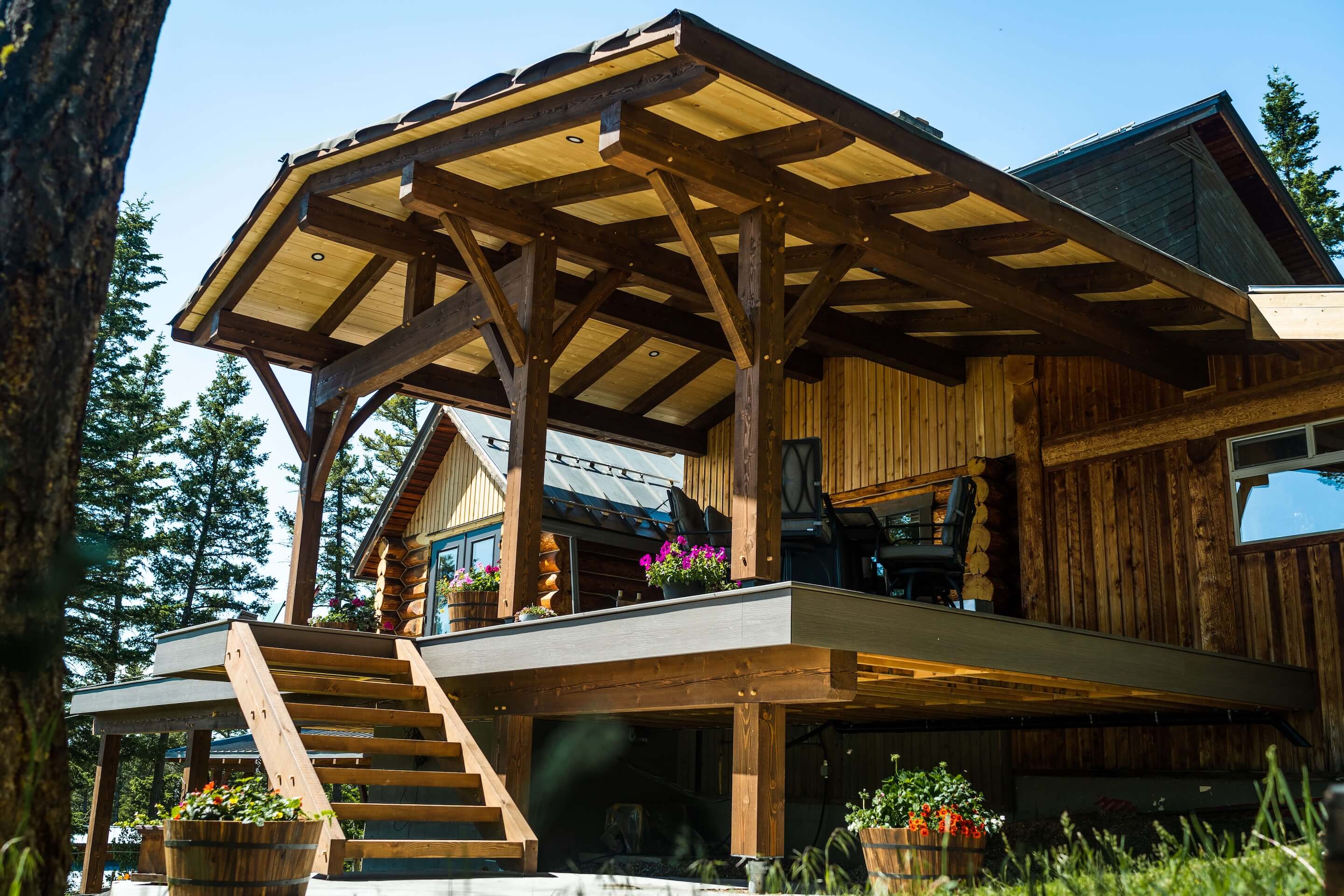 Beautiful Canadian timber frame deck and outdoor living space by Smith Timber Works, featuring exposed wood beams, a covered patio, and stairs, showcasing custom design and craftsmanship in British Columbia.