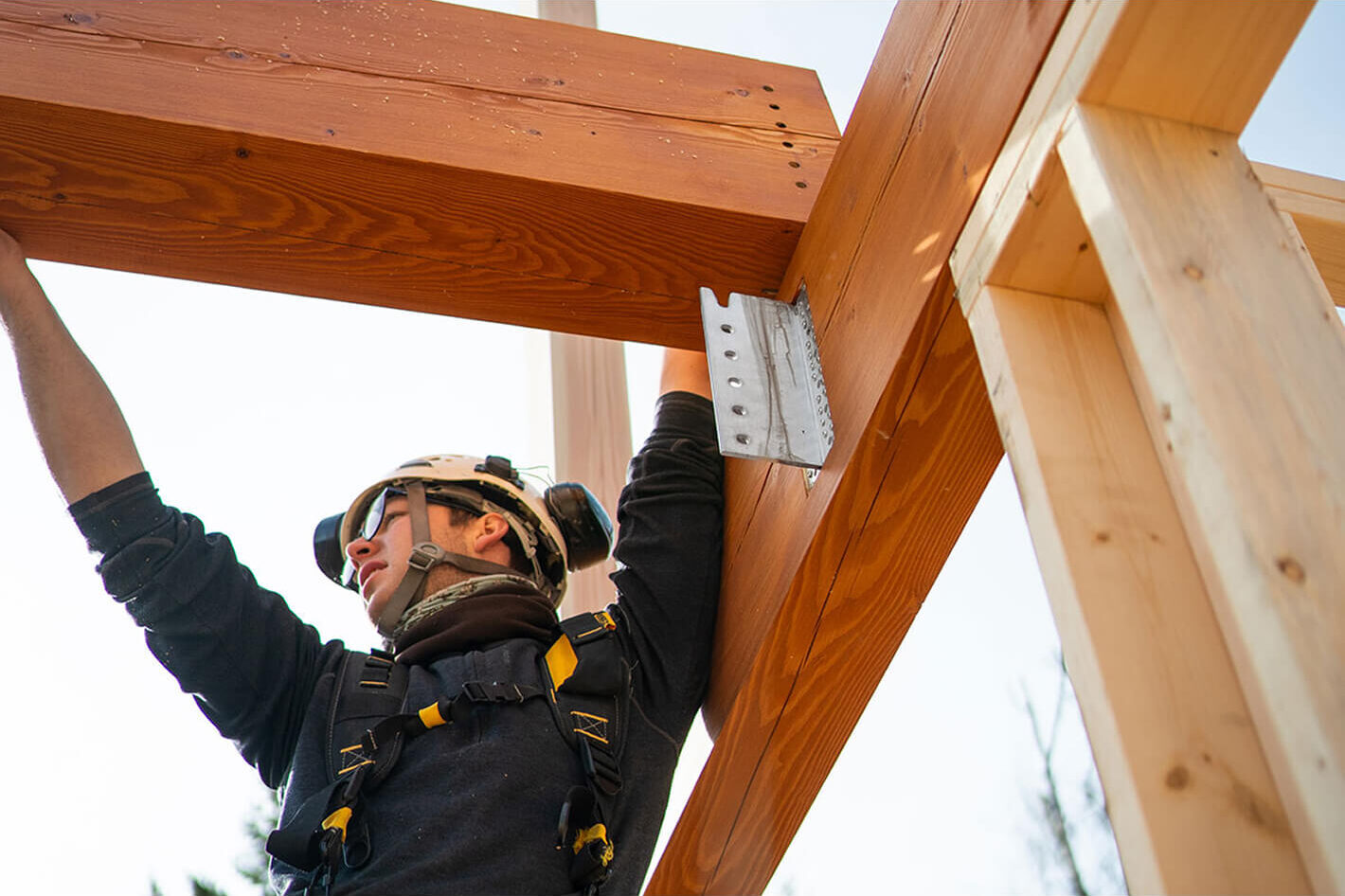 Timber framer positioning a structural beam with precision during post-and-beam assembly for a Smith Timber Works project.