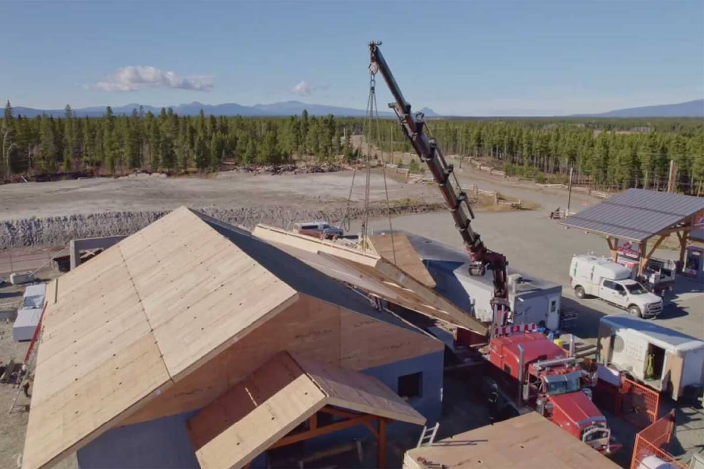 Aerial view of crane positioning roof panels during a Smith Timber Works prefabricated building installation in a remote location.