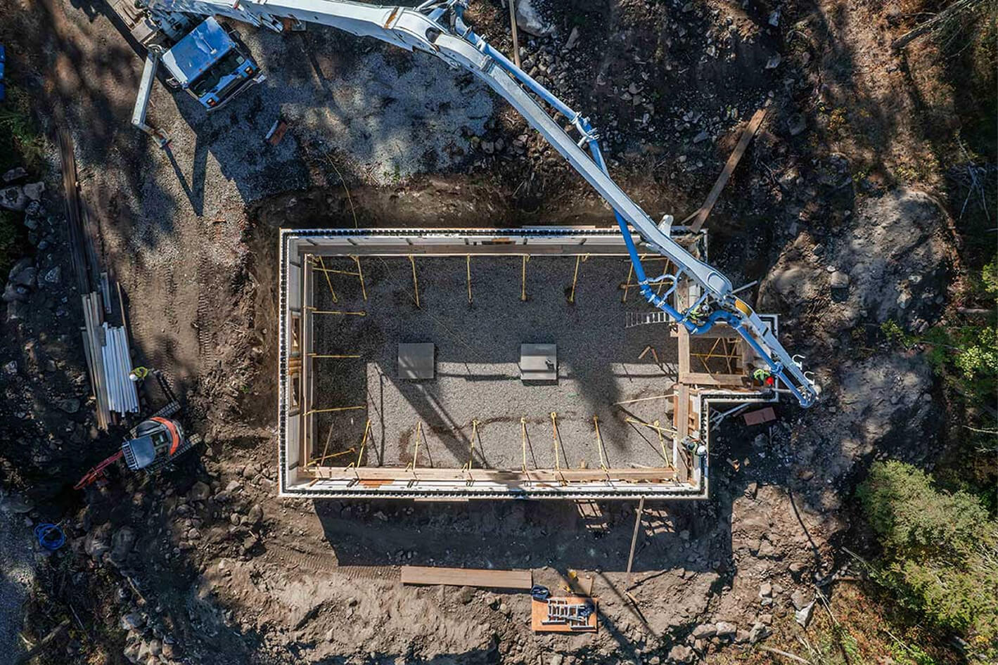 Aerial view of concrete foundation pour underway at a remote building site for a Smith Timber Works prefabricated structure.