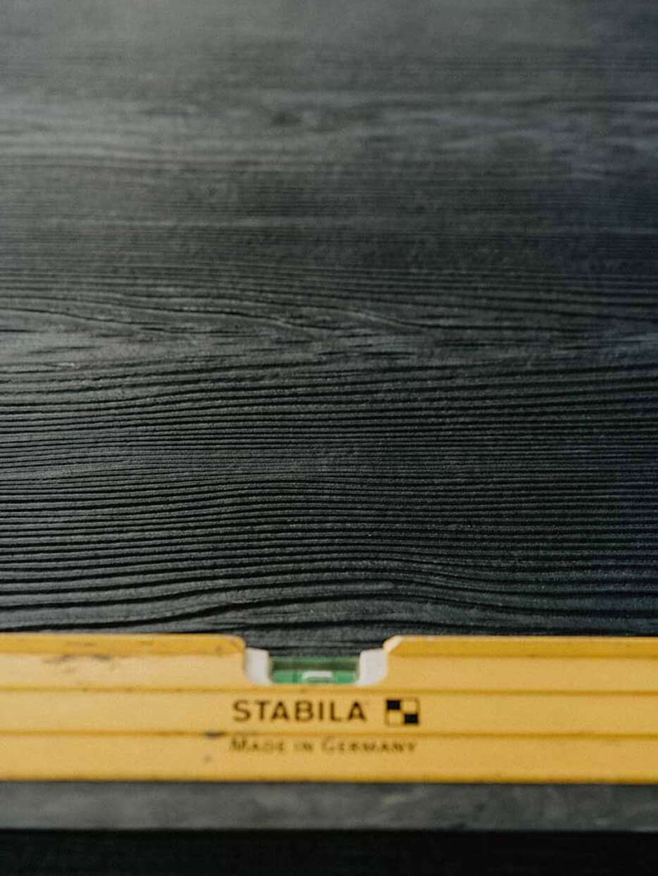 Yellow level resting on textured black siding, showcasing precise exterior finish work by Smith Timber Works.