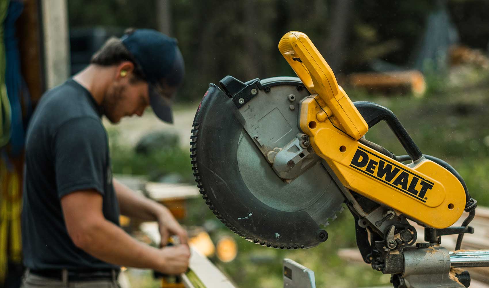 Carpenter using a DeWalt miter saw on a timber framing project, demonstrating the precision and craftsmanship by Smith Timber Works in British Columbia.