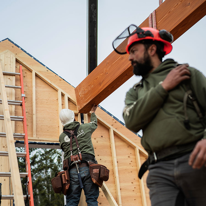 Smith Timber Works crew guiding a timber beam into place on a prefabricated wall panel.