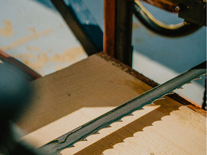 Close-up of a bandsaw cutting through timber, highlighting the precision and custom nature of the fabrication process at Smith Timber Works.