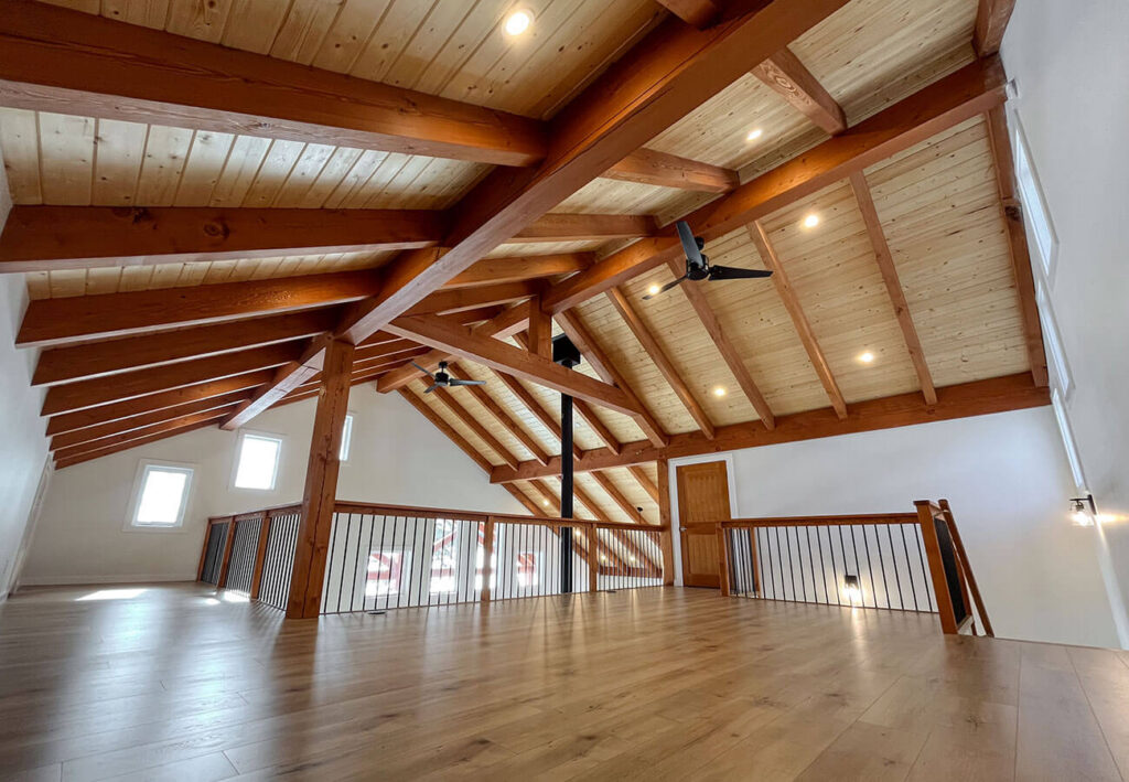 An interior view of a home showcasing a large, open space with a prominent timber frame roof structure.